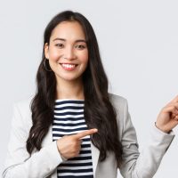 Business, finance and employment, female successful entrepreneurs concept. Confident professional female asian real estate broker showing good deal, pointing upper right corner and smiling.